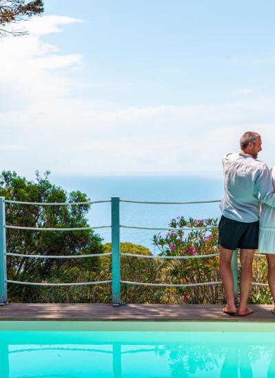 Coppia abbracciata, vista mare e piscina, atmosfera serena e romantica.