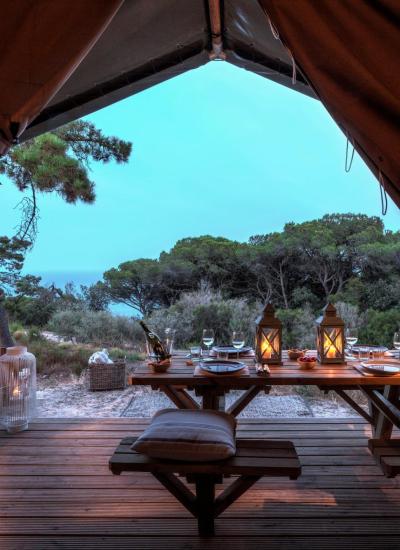 Romantisches Abendessen im Zelt, Natur und Laternen, ruhige Atmosphäre.