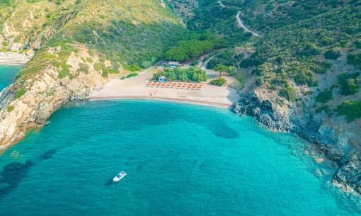 Spiaggia isolata con acque cristalline e barca solitaria.