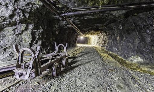 Tunnel minerario con carrello arrugginito, atmosfera di mistero e abbandono.