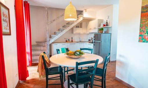 Cucina accogliente con tavolo rotondo e scale, colori caldi e vivaci.