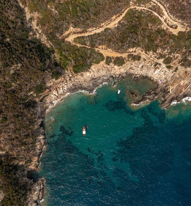 Aerial view of rocky coast, crystal-clear sea, peace and adventure.